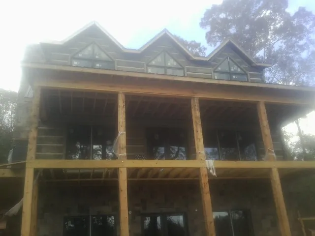 Dormers and porch framing on a large log home under construction — Roof Coating work by our crew in Ruby