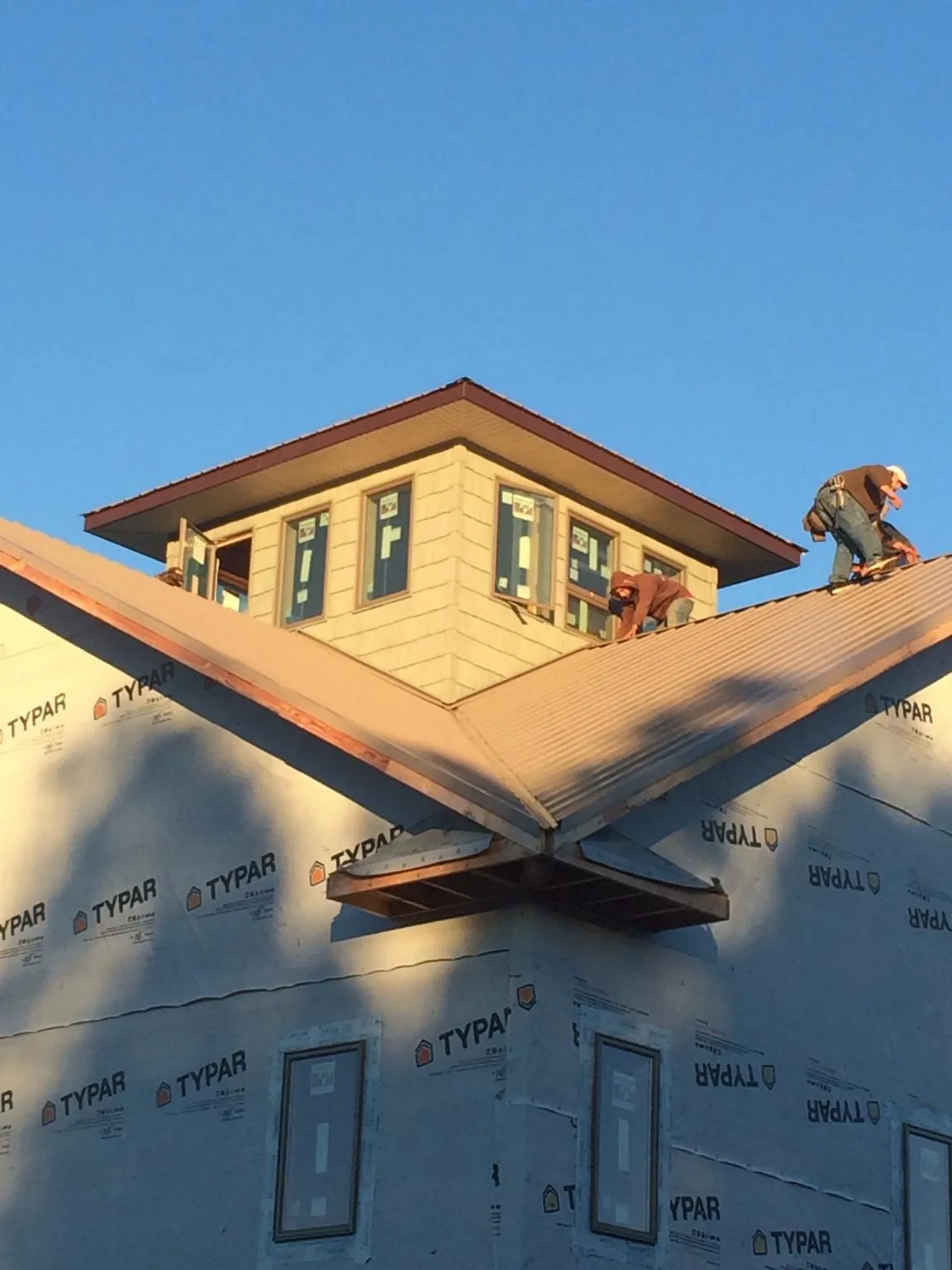 Roofers working around a rooftop cupola on a new metal roof at sunset — Roof Waterproofing in Ruby by Roofing Brothers